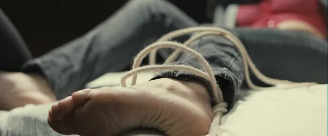 Gemma Arterton lying on a bed in a dramatic screen scene.
