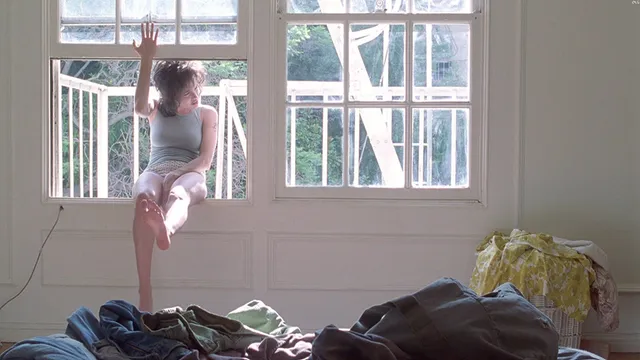 Angelina Jolie seated beside a window with the bottom of a bare foot visible.