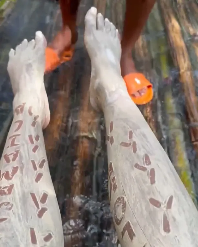 Carlacia Grant shown with bare feet and lower legs covered in pale clay.