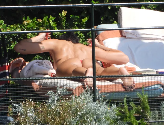 Dua Lipa: reclining barefoot on a garden lounger.