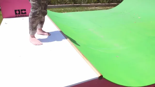 Avril Lavigne standing barefoot on a deck beside a green backdrop.