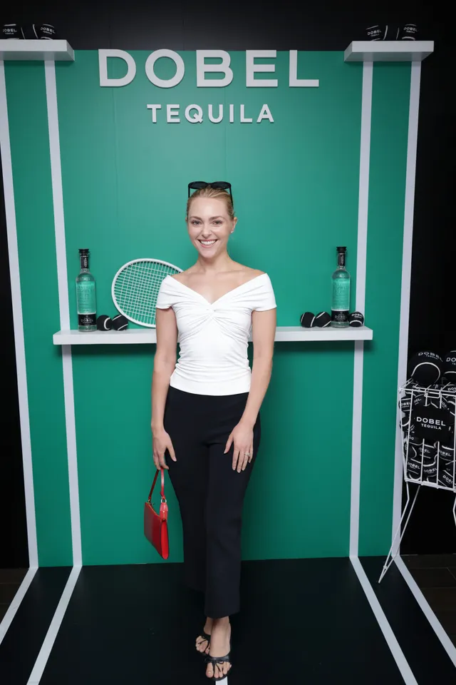 AnnaSophia Robb posing at an event in a white top and dark skirt.