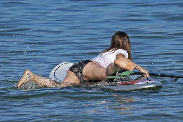 Olivia Wilde lying on a paddleboard on the water.
