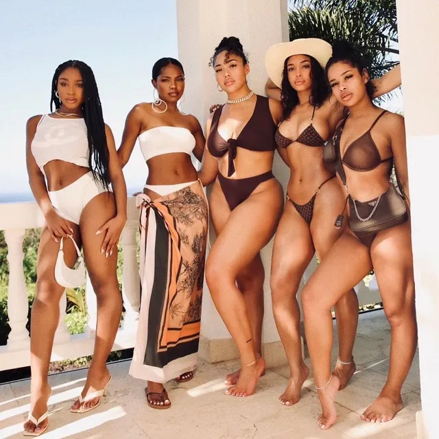 Ryan Destiny posing with friends in coordinated swimwear and flat sandals.