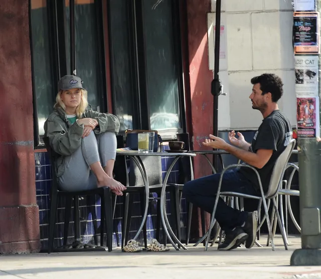 Alice Eve sitting at an outdoor cafe opposite a companion.
