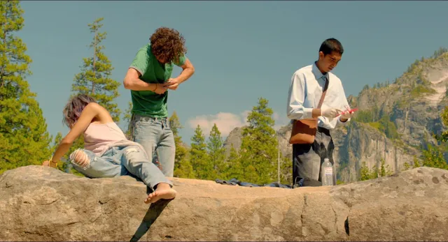 Zoë Kravitz sitting on a rock with other performers in a scene.