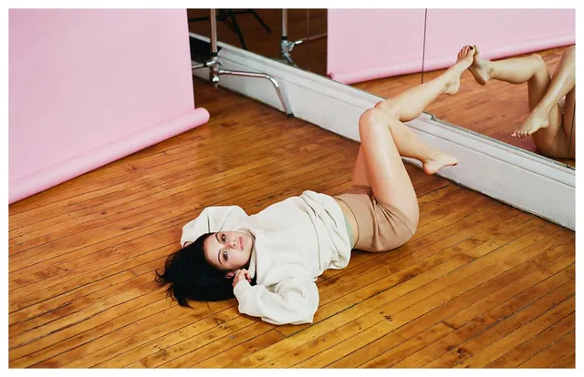 Ariel Winter lying on a wooden floor for a portrait.