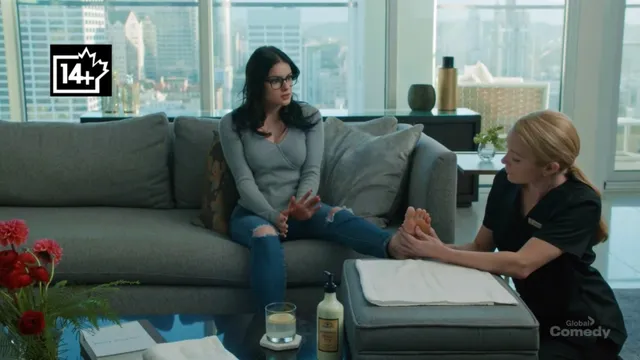 Ariel Winter sitting on a sofa with a companion during a screen scene.
