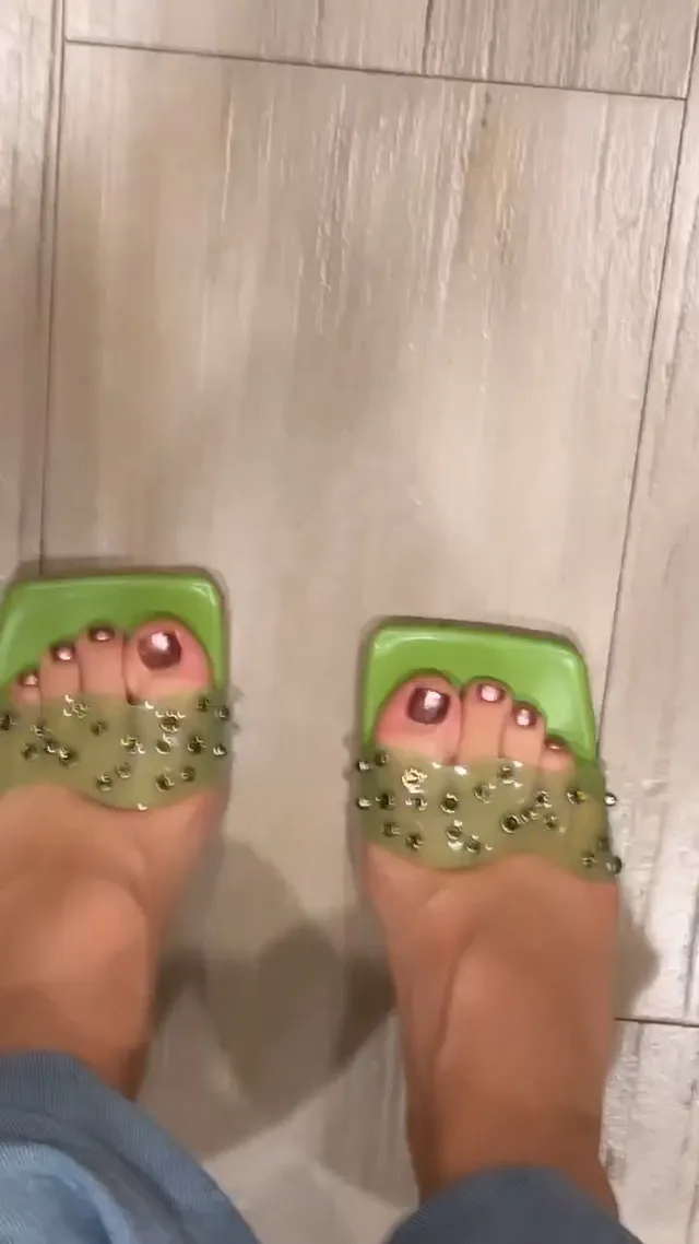 Isabela Merced showing green embellished open-toe heels with painted toenails.