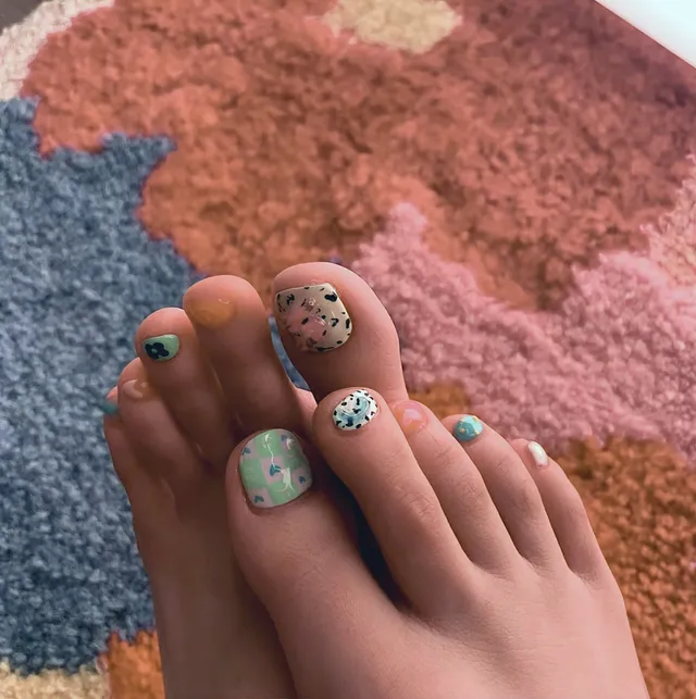 Jisoo showing her decorated toenails above a patterned rug.