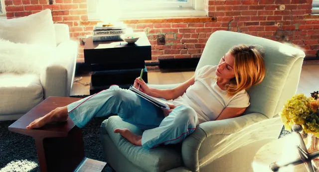Sienna Miller reclining on an armchair with her bare feet raised.
