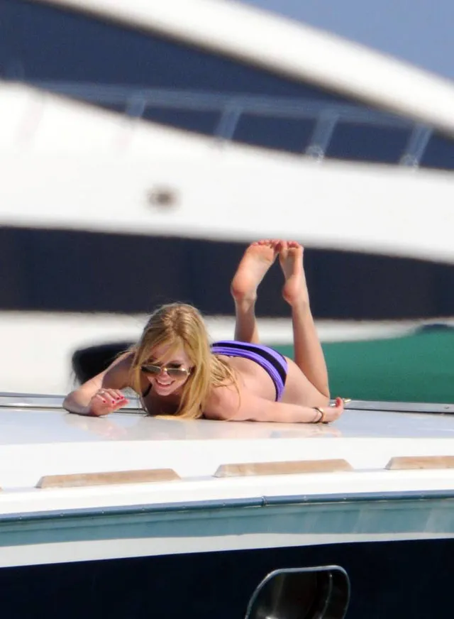 Avril Lavigne lying on a boat with her bare soles raised.