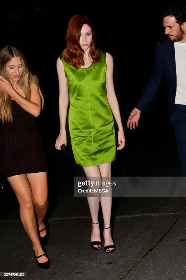 Karen Gillan walking in a green dress and heels beside guests.