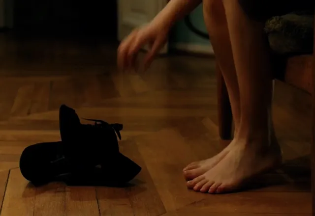 Léa Seydoux standing beside black shoes in a screen scene.