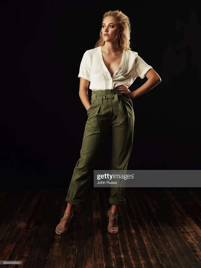Maika Monroe wearing green trousers and heels in a studio.