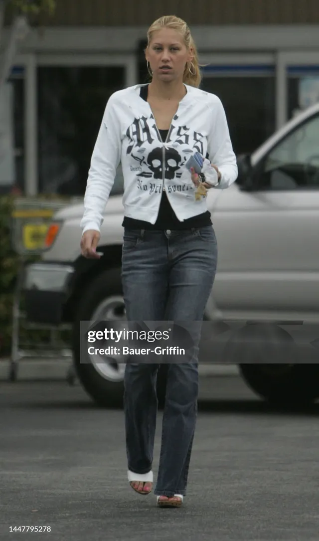 Anna Kournikova walking in pale heels, jeans and a white casual top.