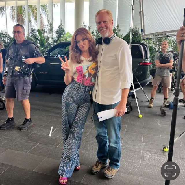 Isla Fisher standing beside a companion at an indoor gathering.