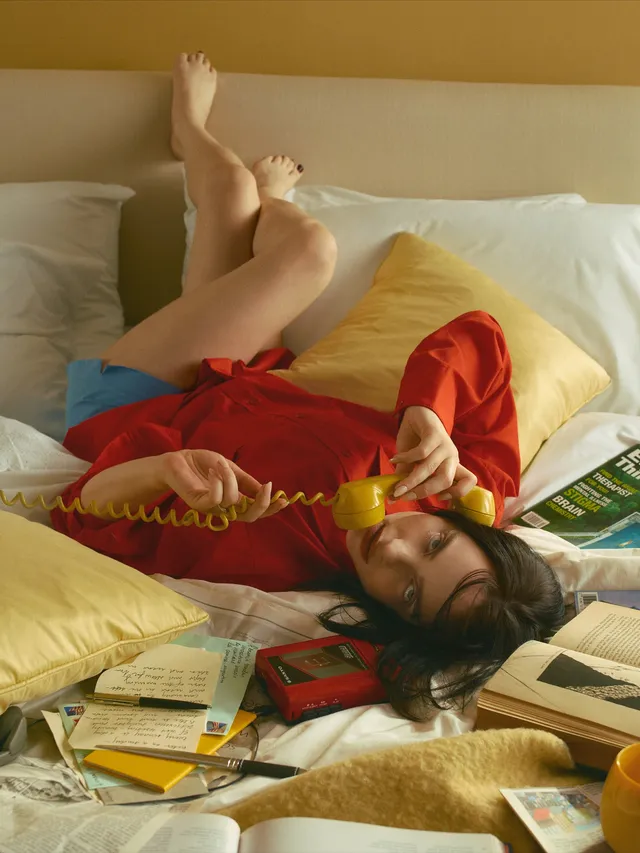 Billie Eilish a reclining red-shirt screen scene with bare feet raised.