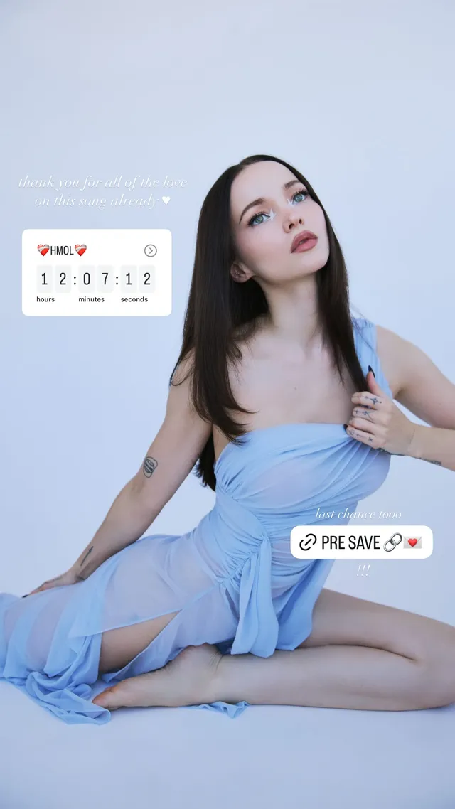 Dove Cameron posing barefoot in a pale blue dress.