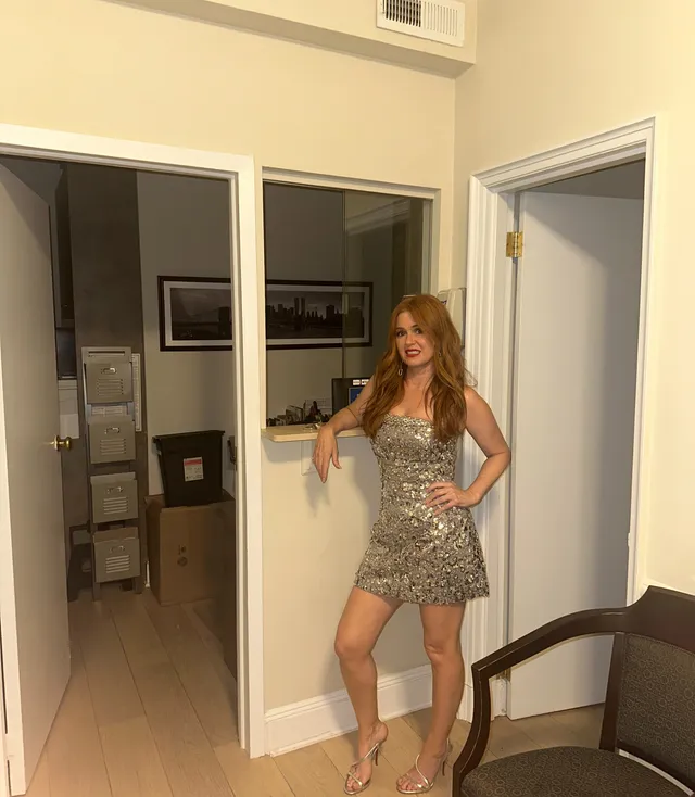 Isla Fisher posing indoors in a short patterned dress.