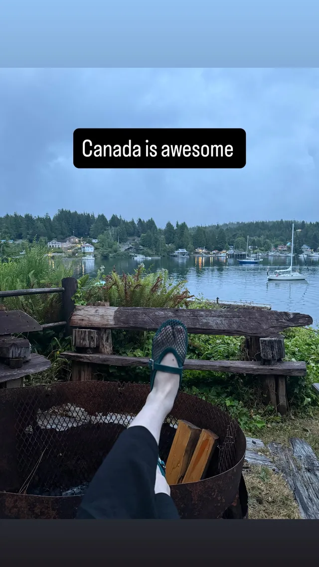 Sophie Thatcher resting a foot in a white sock and mesh shoe beside a lake.