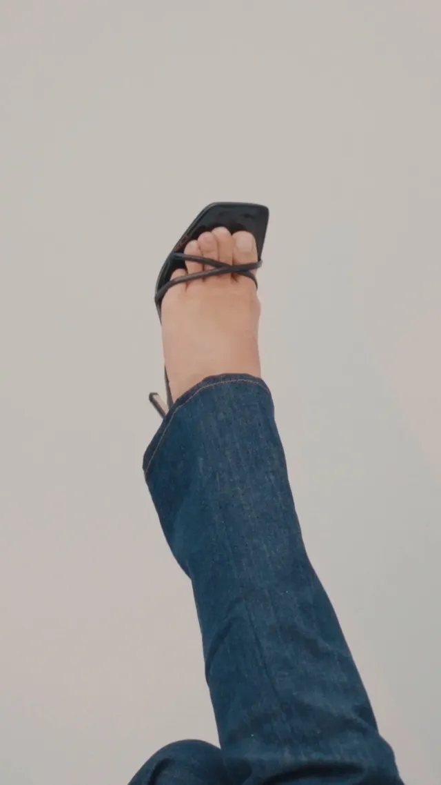 Tate McRae showing a black strappy heel beneath jeans.
