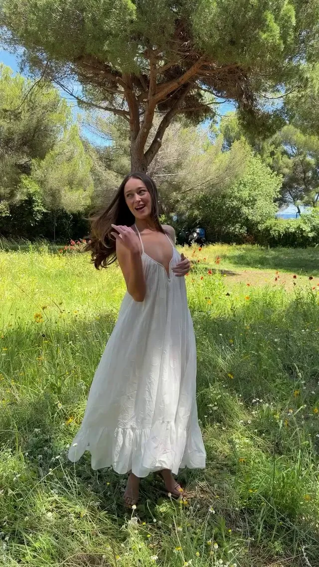 Alycia Debnam-Carey standing in a garden in a flowing white dress.
