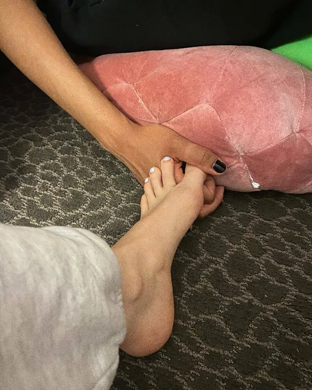 Dove Cameron showing a bare foot beside a pink cushion.