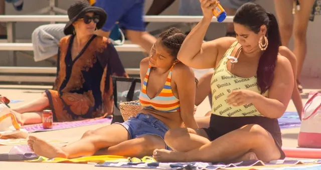 Sierra Capri sitting on a pool deck in a striped top and shorts.