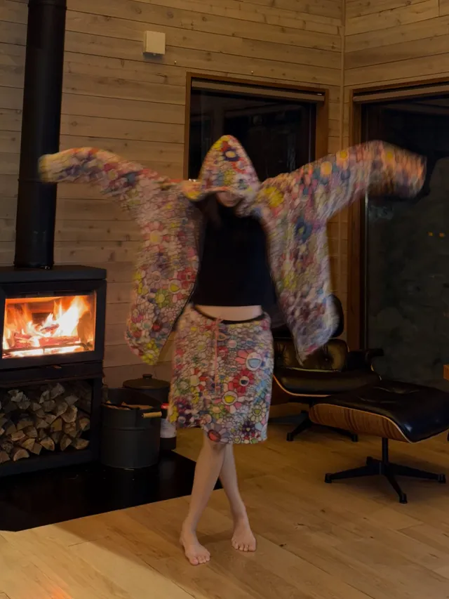 Lisa (Lalisa Manobal) dancing barefoot beside a fireplace in patterned shorts and a jacket.