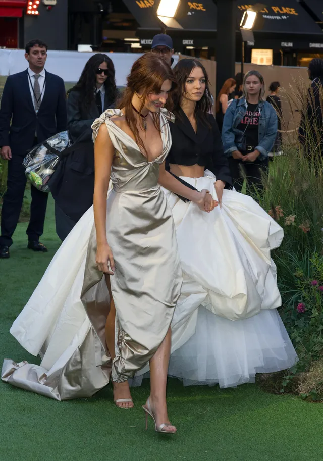 Daisy Edgar-Jones walking with a companion at a premiere in a silver gown.