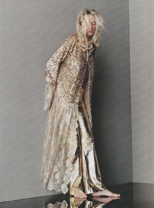 Uma Thurman standing barefoot in a long patterned dress.