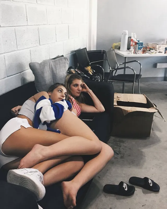 Sophie Nélisse reclining barefoot beside another woman on a sofa.