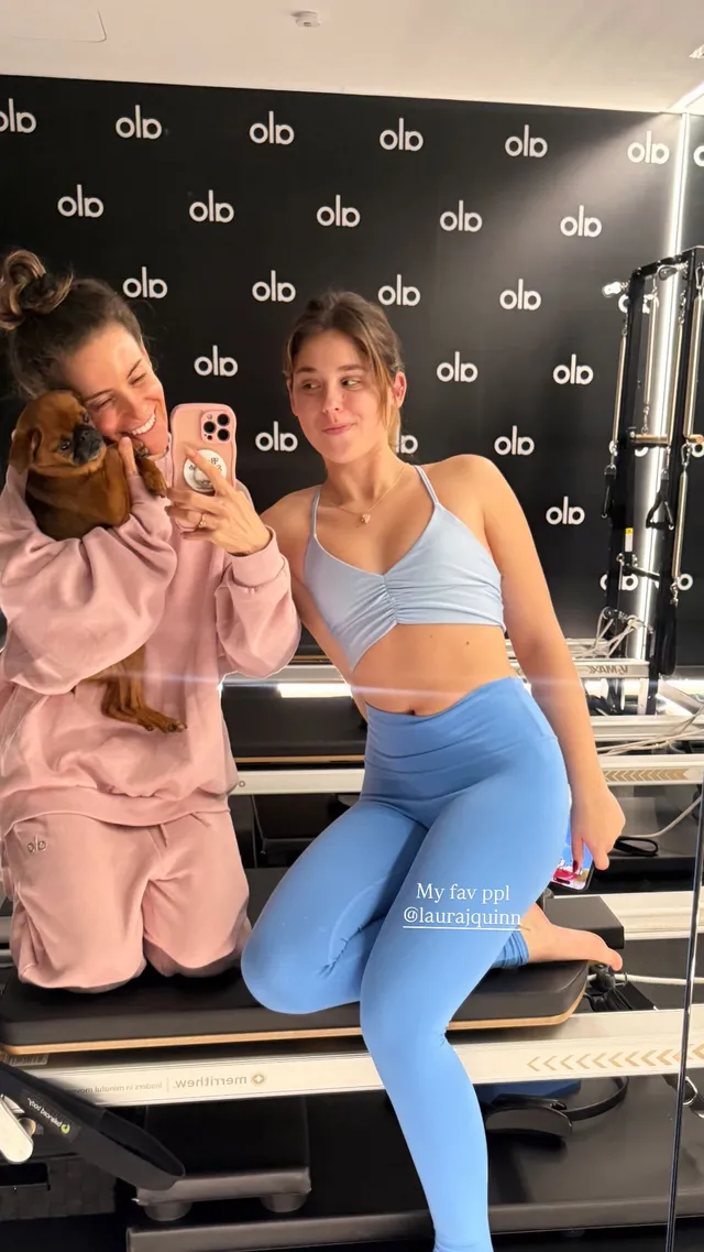 Nicole Wallace taking a mirror selfie with a friend in a blue workout outfit.