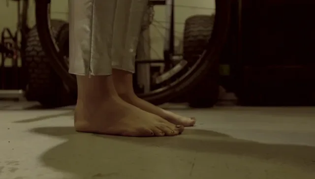 Tove Lo standing barefoot beside a wooden table.
