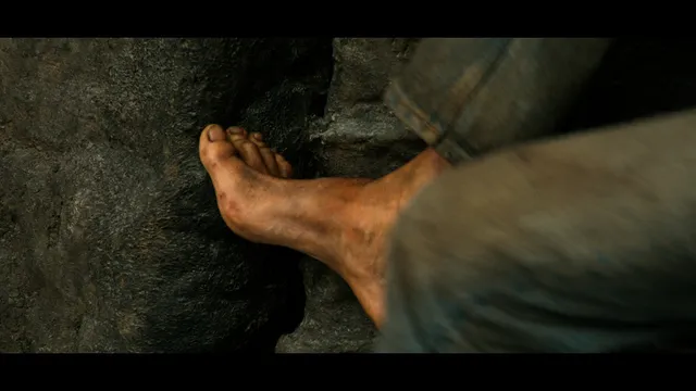 Charlize Theron a close screen detail of a bare foot resting on stone.