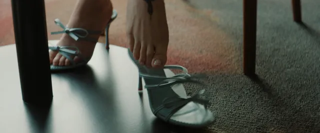 Dove Cameron wearing pale blue strappy heels indoors.