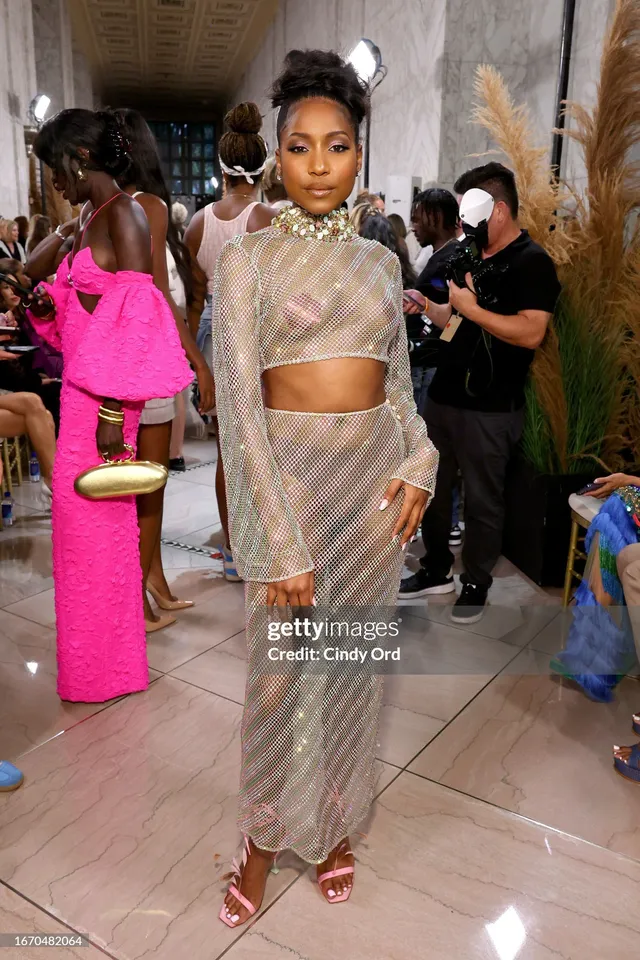 Carlacia Grant posing in a silver skirt set and pink heels indoors.