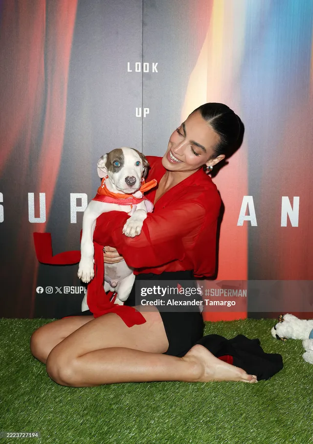 María Gabriela de Faría kneeling barefoot on artificial grass while holding a dog.
