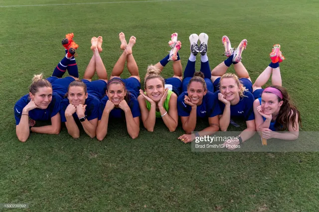Alex Morgan lying on grass beside teammates with her bare feet raised.