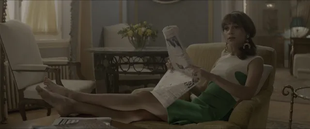Alicia Vikander reclining on a sofa in a screen scene.