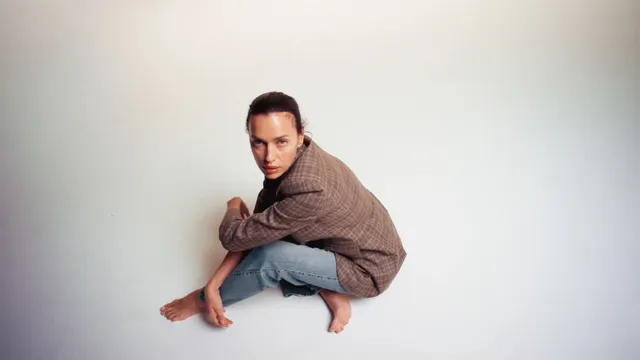 Irina Shayk a crouched studio pose in jeans.