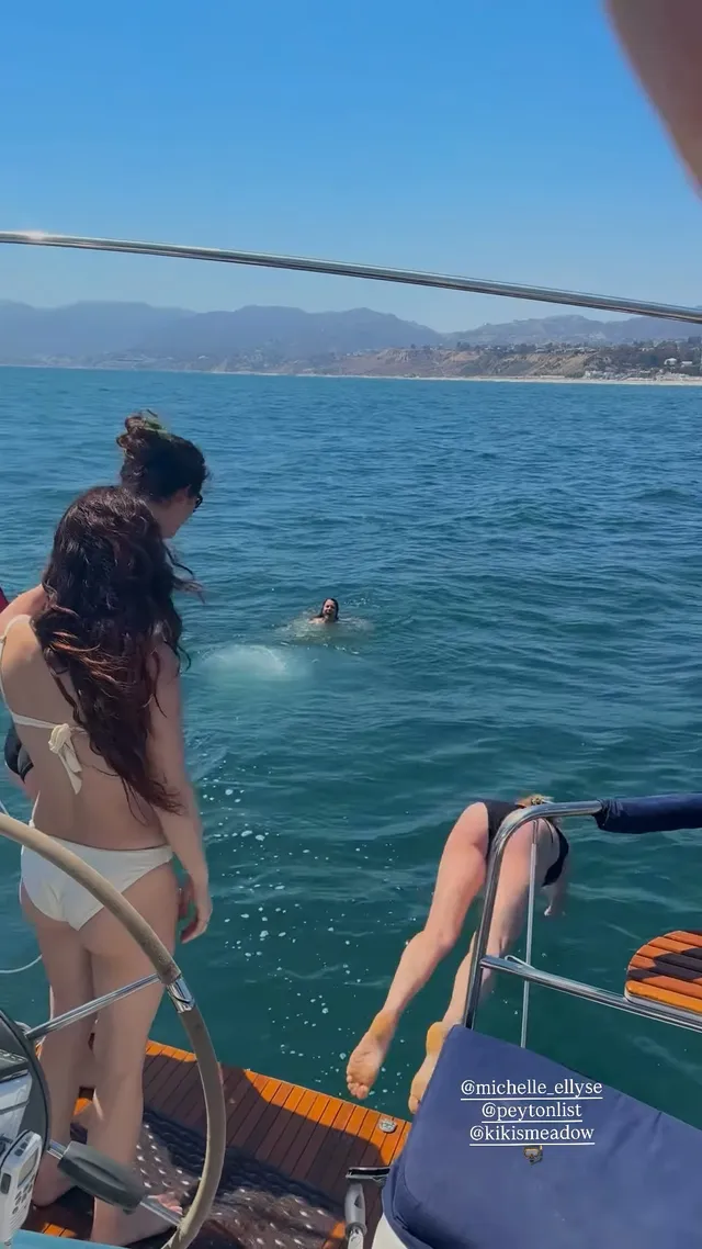 Peyton List standing beside swimmers on a boat.