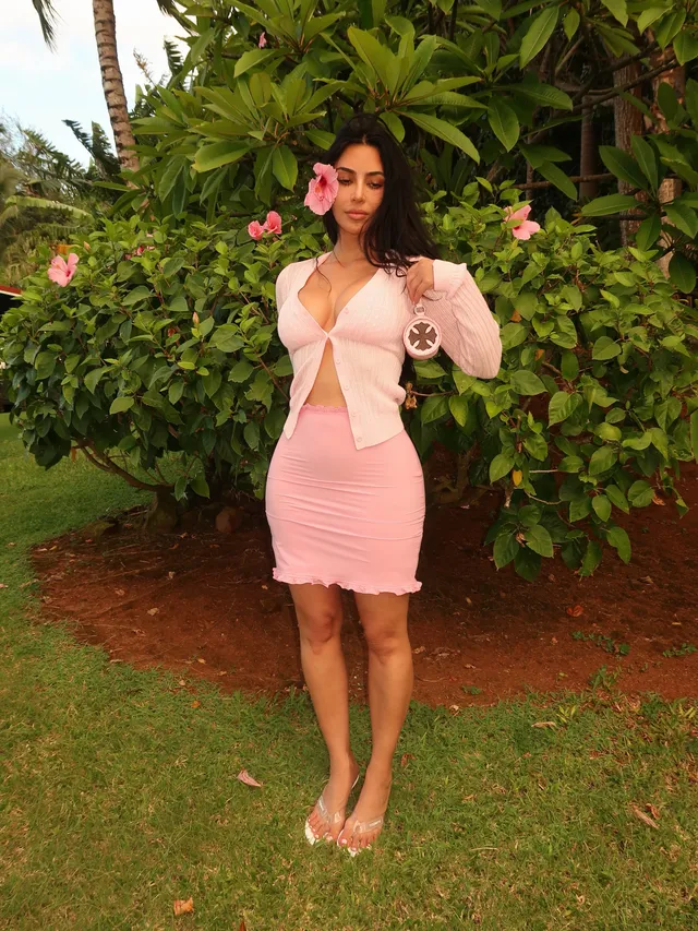 Kim Kardashian standing on grass in a pink dress.