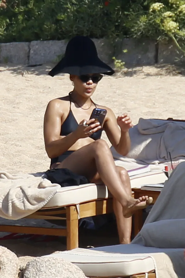 Tessa Thompson sitting on a lounger in a wide brimmed hat.