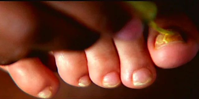 Rosario Dawson resting a bare foot with pale nail polish.