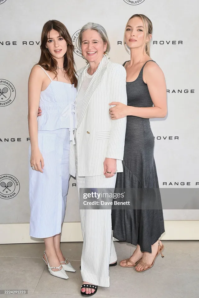 Jodie Comer posing with other guests in a long grey dress.