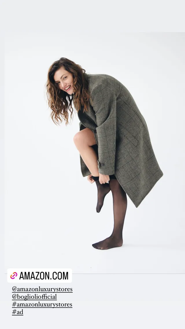 Phoebe Tonkin adjusting dark hosiery during a studio portrait.