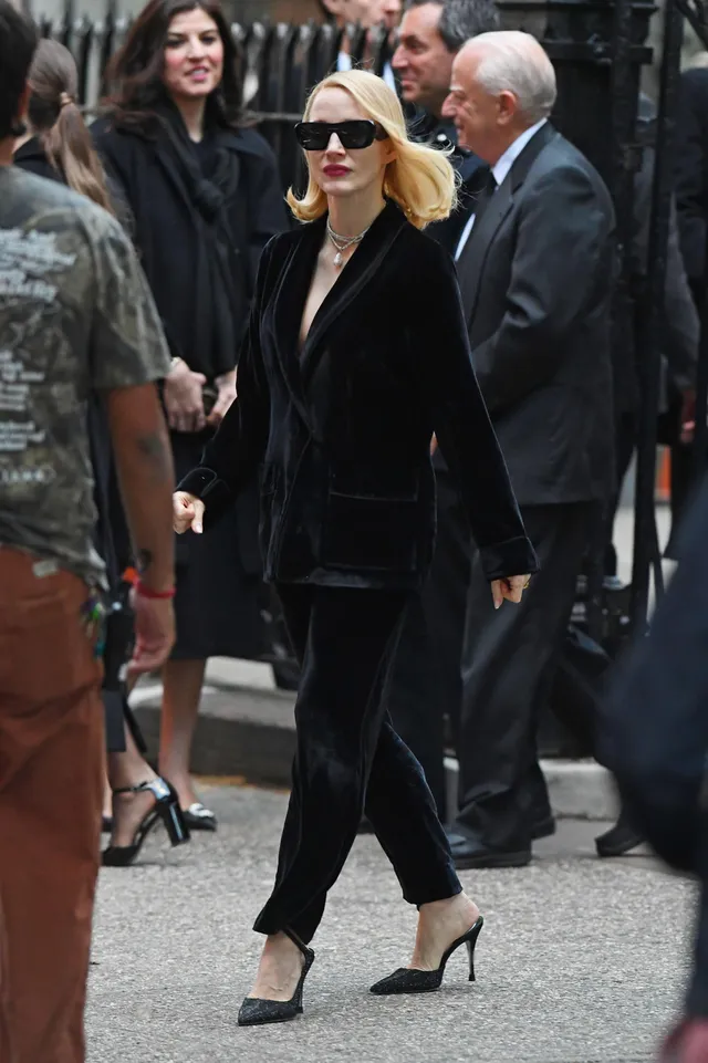 Jessica Chastain walking through a crowd in a black trouser suit.
