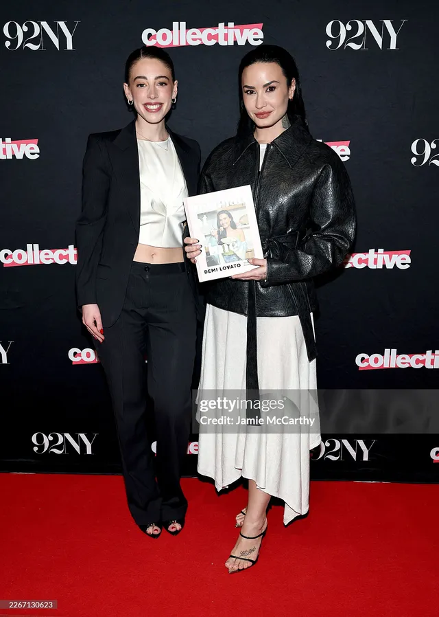 Demi Lovato standing beside another person in a white skirt and strappy heels.